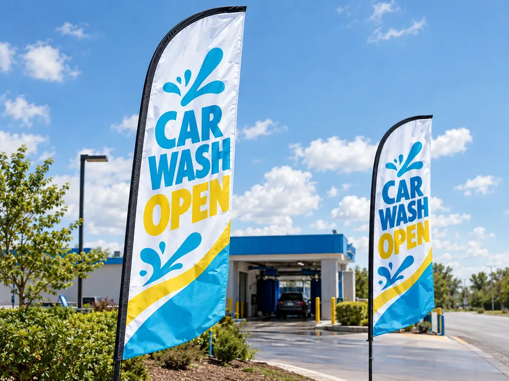 Two blue and yellow Car Wash Open feather flags at a car wash entrance